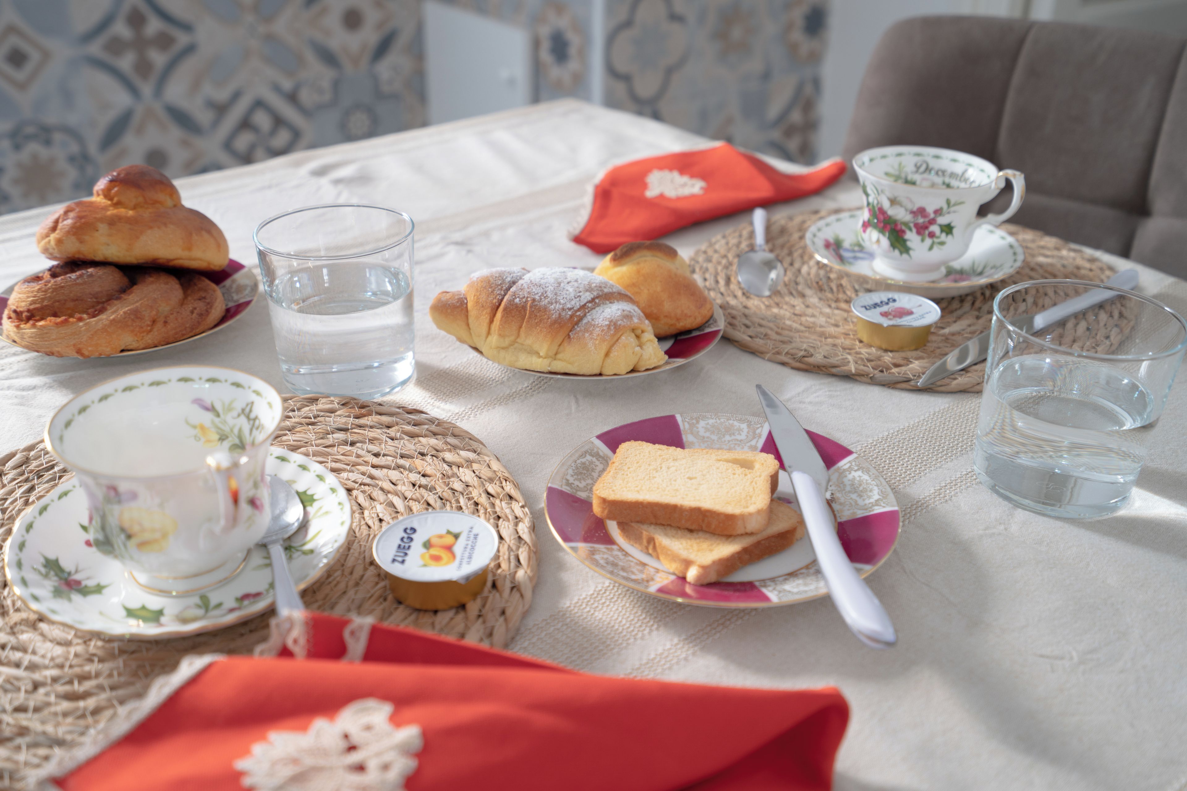 Une table dressée avec du pain, du beurre, de la confiture et une tasse de thé.