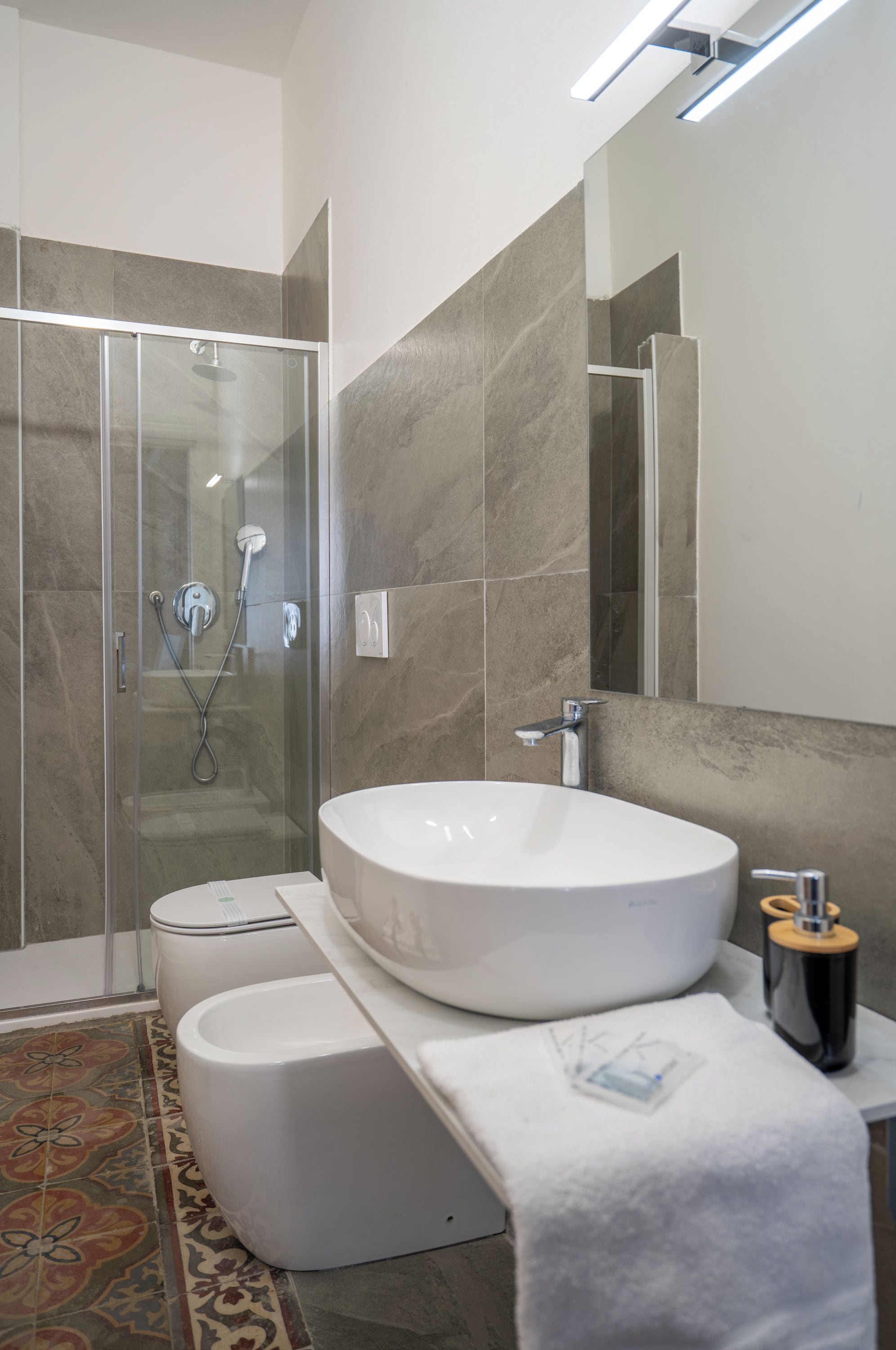 Un bagno moderno con un lavandino bianco grande, una cabina doccia in vetro e uno specchio sopra il lavandino.