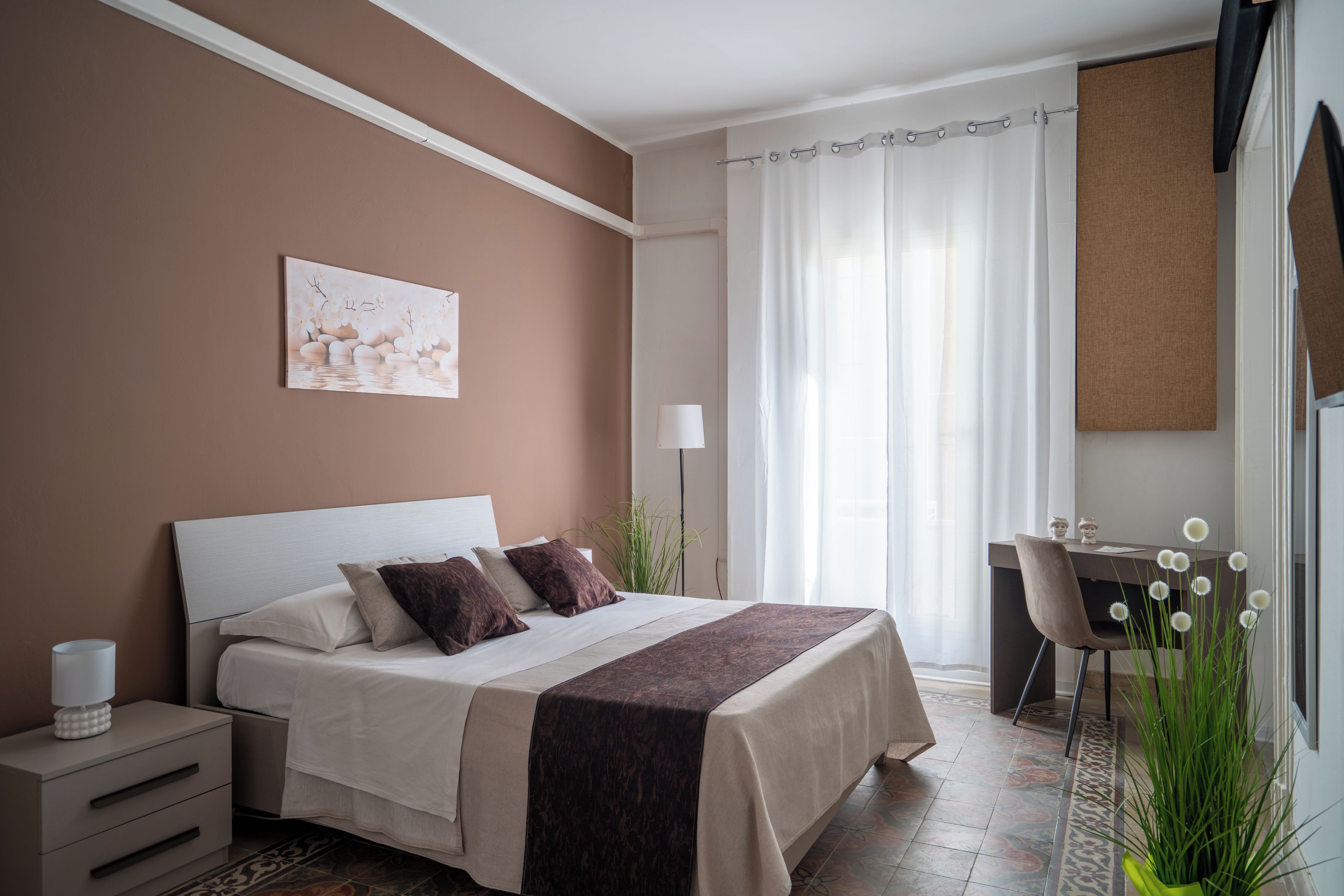 Ein Schlafzimmer mit einem Bett, einem Nachttisch, einer Lampe und einem Schreibtisch mit Stuhl.