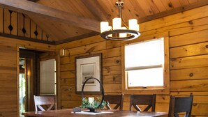 A wooden interior with a dining table, chairs, a bench, a hanging light fixture, and a window. - Northwoods of Lake Geneva. Pet-Friendly! (Williams Bay)