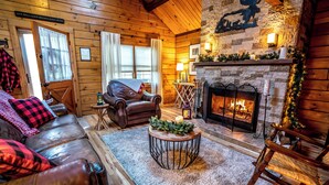 A cozy log cabin interior with a leather sofa, a fireplace, and a rustic decor. - Northwoods of Lake Geneva. Pet-Friendly! (Williams Bay)