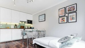 Ein modernes Schlafzimmer mit einem Bett, einem Schreibtisch mit Stühlen und einer Küchenzeile.