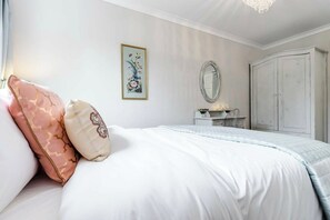 A bedroom with a bed, a dresser, a mirror, and a wardrobe.