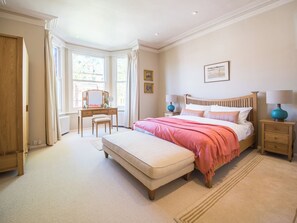 A bedroom with a large bed, a bedside table, a dresser, a window, and a mirror. - Inviting 2BD Victorian Flat, Near Hampstead (London)
