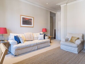 A living room with a sofa, a chair, a lamp, and a framed picture on the wall.