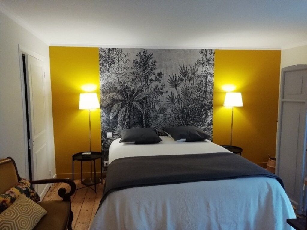 Un dormitorio con una cama, dos lámparas de noche, una mesita de noche, una silla y un tapiz en la pared.