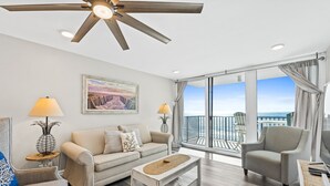Un salon spacieux doté d’une grande fenêtre, d’un ventilateur de plafond et offrant une vue sur l’océan.