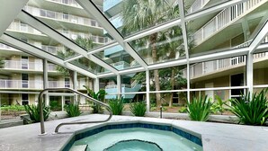 Un hôtel moderne doté d’une piscine centrale, de nombreux balcons et d’un aménagement paysager luxuriant.