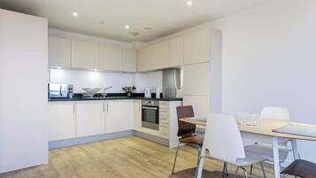A modern kitchen with white cabinets, a black countertop, and a dining area with a table and chairs.