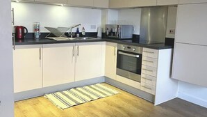 Een moderne keuken met witte kasten, een roestvrijstalen oven en een zwart aanrecht.