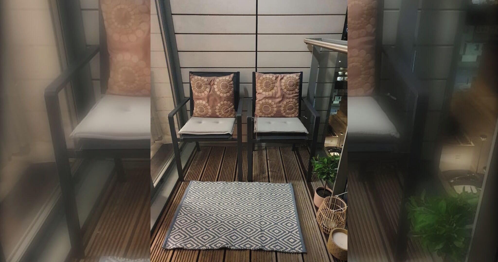 A balcony with two chairs, a patterned rug, and a potted plant.