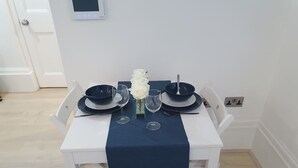 Ein Esstisch mit Tellern, Schüsseln und Weingläsern, platziert auf einer weißen Tischdecke mit blauem Tischläufer.