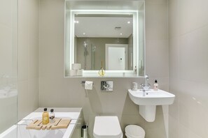 A modern bathroom with a bathtub, toilet, and sink.