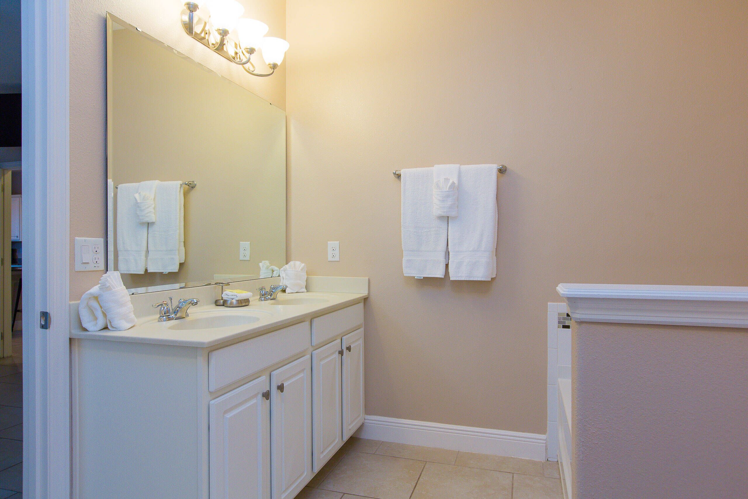 A bathroom with a double sink, a large mirror, and two towels hanging on the wall.