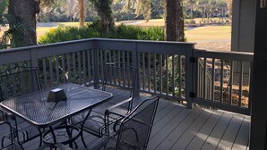 A covered outdoor area with a table and chairs, overlooking a golf course.