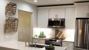 A modern kitchen with white cabinets, stainless steel appliances, and a central island with stools.