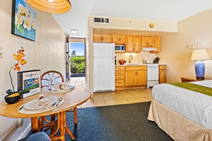 Quarto de hotel compacto com cozinha compacta, área de refeições e uma cama.