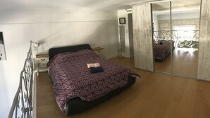 A bedroom with a bed, bedside table, mirror, and a wardrobe. - Charming apartment in the escutcheon (Montpellier)