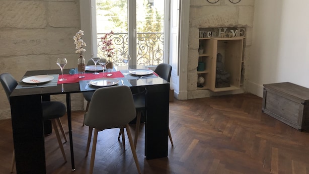 A dining area with a table set for four, a bicycle mounted on the wall, and a small Buddha statue in a wooden cabinet. - Charming apartment in the escutcheon (Montpellier)