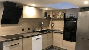 A modern kitchen with a dishwasher, oven, and a Bosch refrigerator. - Charming apartment in the escutcheon (Montpellier)