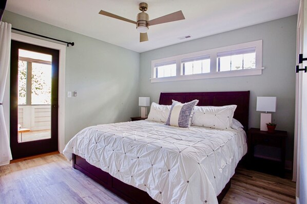 A bedroom with a bed, two bedside tables with lamps, a ceiling fan, and a window with multiple panes. - Luxe DT Experience: 5 Star Beds | Chef's Kit & Spa (Black Mountain)