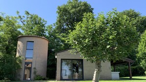 Un edificio moderno con una torre cilindrica, un ingresso con porta in vetro e una piccola zona coperta.