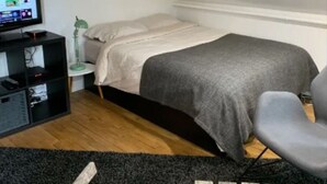 A bedroom with a bed, a desk, a chair, and a TV.