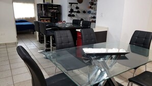 A dining area with a glass table and black chairs, a kitchen area with pots and pans, and a bed in the background. - BONITA CASA CENTRO MTY KIKE (monterrey)