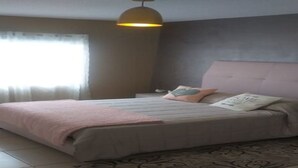 A bedroom with a bed, a bedside table, a lamp, and a window with curtains. - BONITA CASA CENTRO MTY KIKE (monterrey)