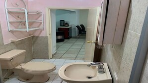 A small bathroom with a toilet, sink, and a metal shelf unit. - BONITA CASA CENTRO MTY KIKE (monterrey)