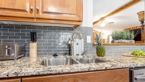A kitchen with granite countertops, stainless steel appliances, and wooden cabinets. - Stunning Custom Ranch in Central Roswell (Roswell)