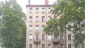 Ein mehrgeschossiges Gebäude mit einer Reihe von Balkonen und einem Geschäft im Erdgeschoss namens "Cerise et Potiron".