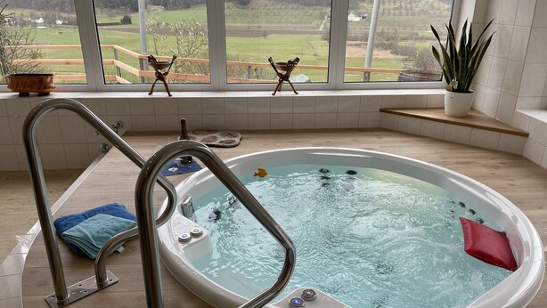 A hot tub with a view of a green landscape through large windows. - 4**** Holiday paradise on Lake Constance (Owingen)