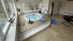 A modern bathroom with a large bathtub, a glass shower enclosure, and a seating area with a chair and a small table. - 4**** Holiday paradise on Lake Constance (Owingen)