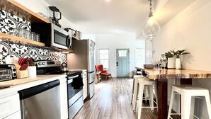 Een moderne keuken met roestvrijstalen apparatuur, een houten aanrecht en een bar met krukken.