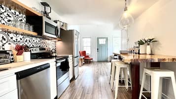 A modern kitchen with stainless steel appliances, a wooden countertop, and a bar area with stools.