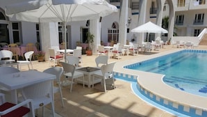 A poolside area with white outdoor furniture, umbrellas, and a pool. - Hotel Sindbad Center Sousse (Sousse)