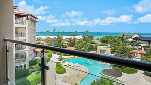 A resort with a pool, palm trees, and a view of the ocean. - OUTSTANDING OASIS 4th FLOOR CONDO At EAGLE BEACH (Oranjestad, Aruba)