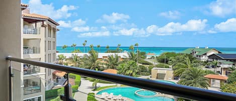 Un resort con piscina, palmeras y vista al océano.