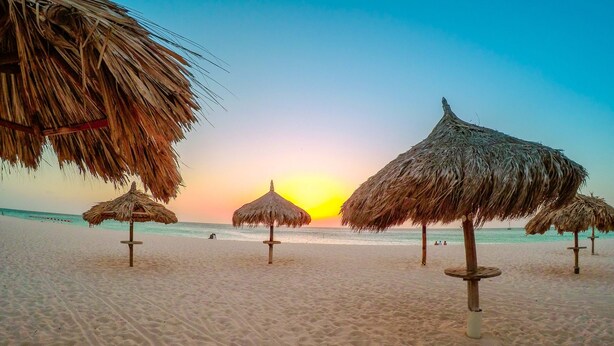 A beach with thatched umbrellas and a clear sky. - OUTSTANDING OASIS 4th FLOOR CONDO At EAGLE BEACH (Oranjestad, Aruba)