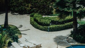 Une piscine dont la profondeur maximale est indiquée à 1,5 mètre, entourée de chaises longues et de palmiers.