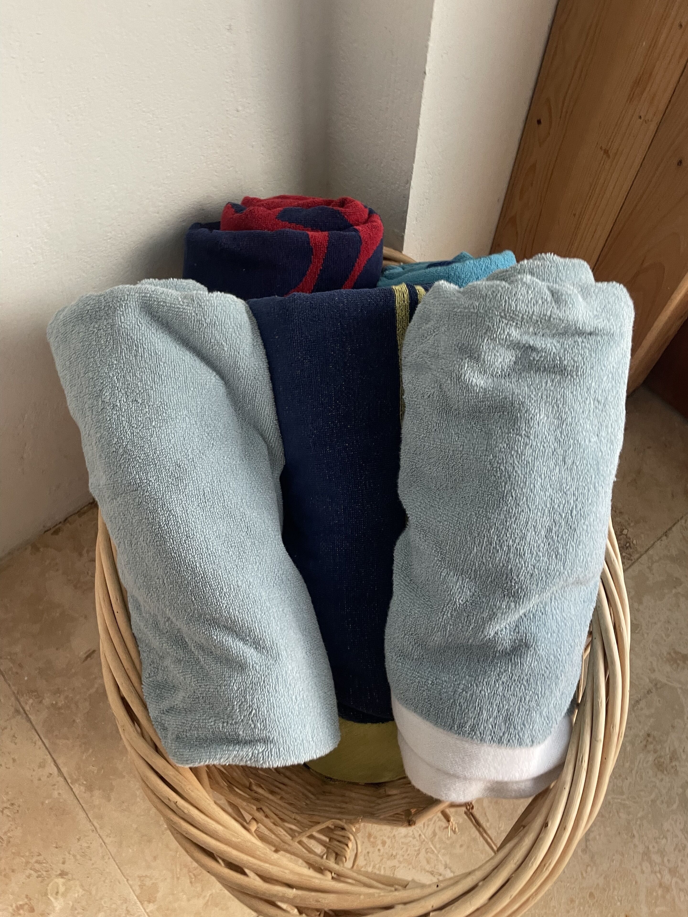 Een rieten mand met gevouwen handdoeken in verschillende kleuren.
