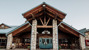 A rustic lodge with a stone facade, wooden beams, and a blue entrance door.