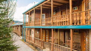 A two-story log cabin with a balcony, wooden railings, and a stone pathway leading to the entrance.