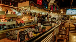 A bar area with shelves of bottles, glasses, and a chalkboard menu.