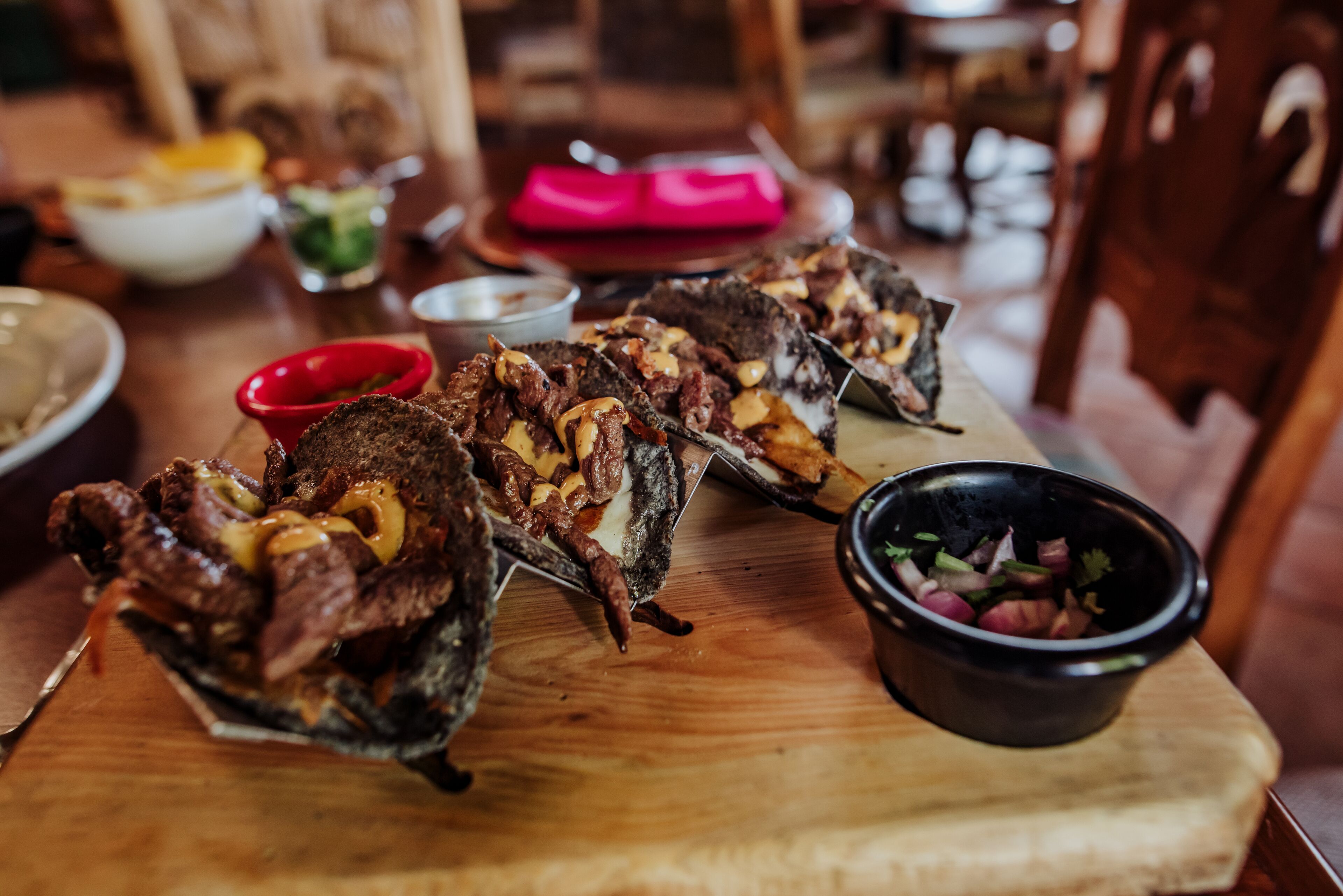 Una mesa de comedor con diversos platos, incluyendo carne ensartada y un tazón de ensalada.