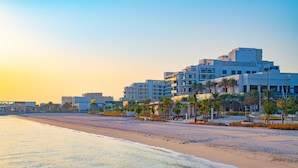 Een hotel aan het strand met meerdere gebouwen, palmbomen en een zandstrand.