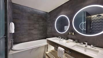 Uma casa de banho moderna com uma banheira grande, duas pias e um lavatório com espelho.