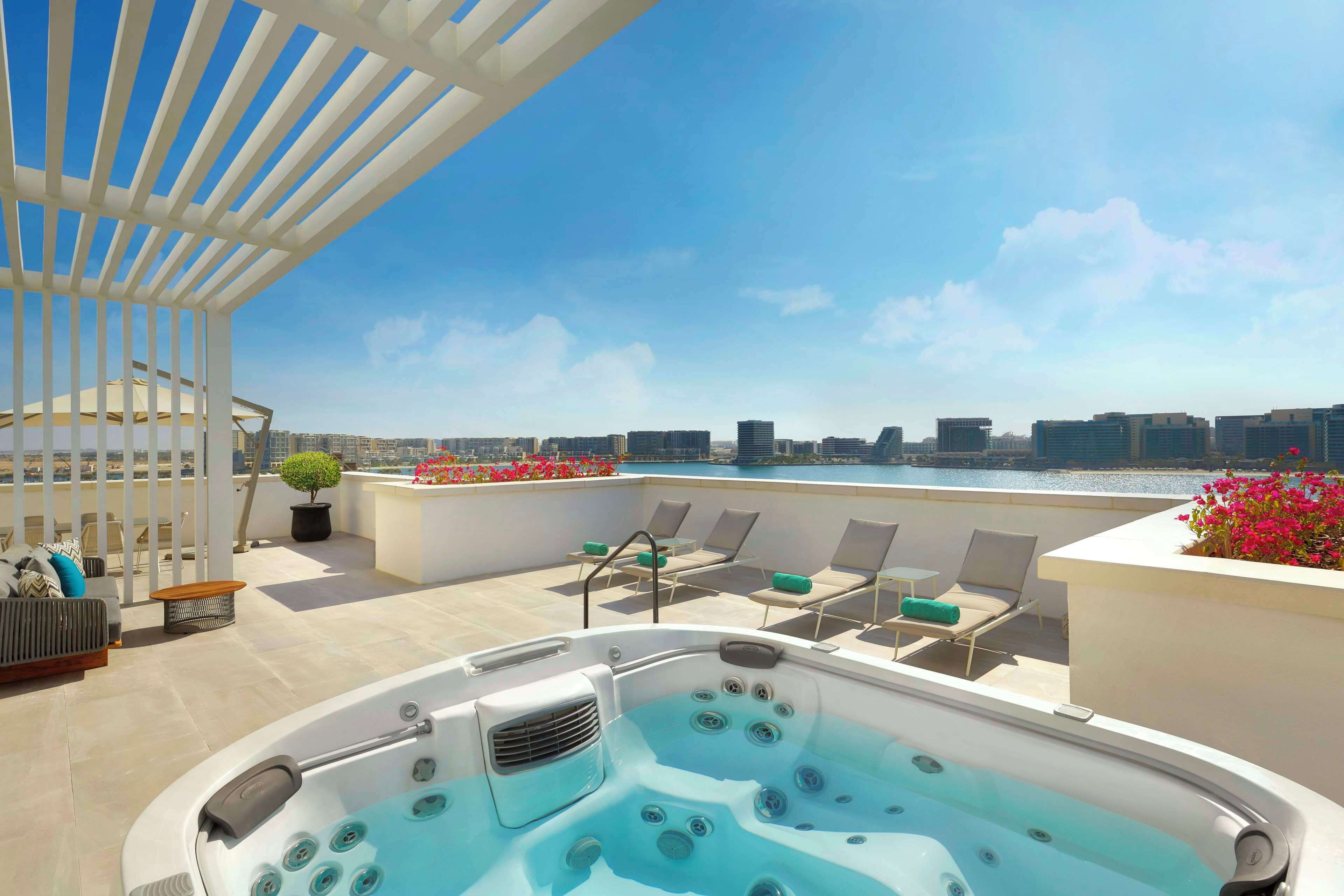 Terraza en la azotea con jacuzzi, sillones de descanso y vistas a la ciudad.