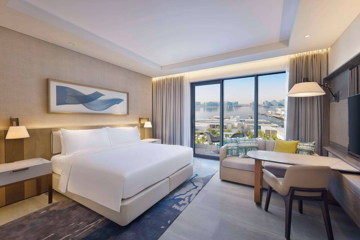 Ein modernes Hotelzimmer mit einem großen Bett, einem Schreibtisch und Blick auf die Stadt.
